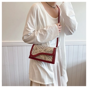 Detail of red embossed leather crossbody bag with vintage tapestry patterns on model