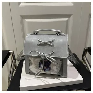 Detail of silver ita bag showing transparent window with anime pins and ribbon bow