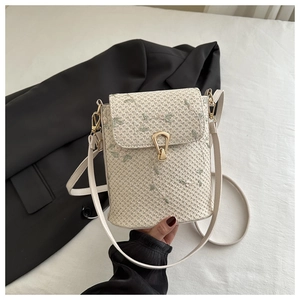Détail du sac bandoulière en paille tissée avec broderies fleurs et fermoir doré