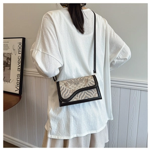 Detail showing vintage wavy pattern crossbody bag with black leather trim worn by a model