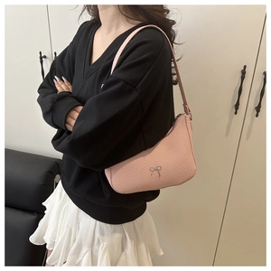 Detailed view of pink crescent bag with woven texture and silver bow detail on model