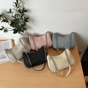 Sac hobo minimaliste avec chaîne en cinq couleurs sur une table en bois clair