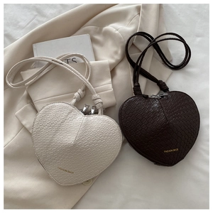 Detail of woven heart-shaped shoulder bags in cream and coffee colors with dual zippers