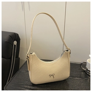 Close-up of cream woven texture shoulder bag with a silver bow metal detail