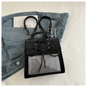 Detail of black ita bag with ribbon bow and transparent mesh pocket on denim fabric