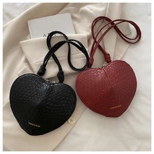 Close-up of heart-shaped bags in black and burgundy with crocodile embossed texture