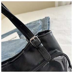 Detail of adjustable silver buckle on black leather tote bag with transparent panel