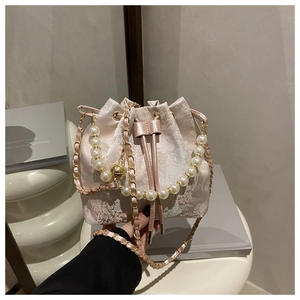 Detail of pink satin bucket bag with floral jacquard, pearl handle and gold bell