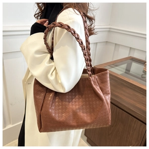 Détail d'un sac cabas marron avec gaufrage en étoile et bandoulières tressées