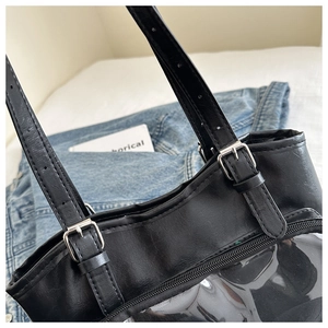 Close-up of black PU leather tote bag featuring adjustable metal buckles and transparent PVC panel