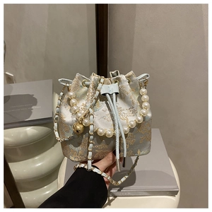 Detail view of floral embroidery on light blue bucket bag with pearl and chain straps
