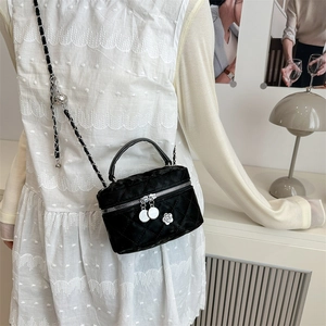 Sac boîte noir matelassé avec chaîne et pendentif camélia porté par un mannequin