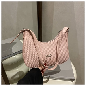 Close-up of pink woven texture shoulder bag with a silver metal bow accent