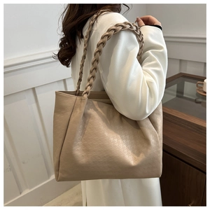 Gros plan sur un sac cabas en cuir beige avec motif pied-de-poule et bandoulière tissée