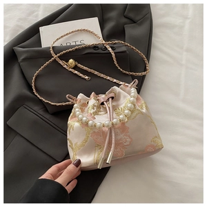 Detail of pink and gold floral embroidery on a bucket bag with pearl handle and chain strap