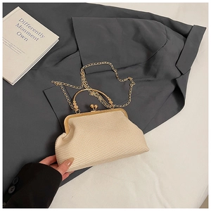 Detail view of woven shell-shaped crossbody bag with gold handle and metal chain strap