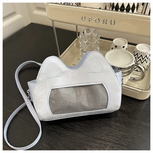 Close-up of a light blue kitten ear design crossbody bag with a mesh window on a table