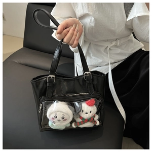 Detail of black leather ita bag with clear window pocket and cute plush dolls decoration