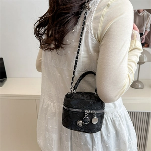 Sac cosmétique noir matelassé avec bandoulière chaîne et breloque camélia porté par mannequin
