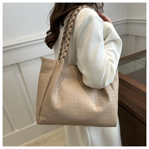 Détail du sac cabas beige avec texture pied-de-poule et anses tressées sur l'épaule