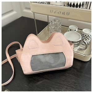 Detailed view of pink cat-ear crossbody bag with grey mesh window on dark wood table