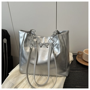 Detail of silver tote bag featuring metallic bow buckle and chunky metal chain strap