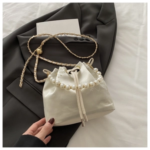 Detail of cream white bucket bag with embroidery, pearl handle and gold chain