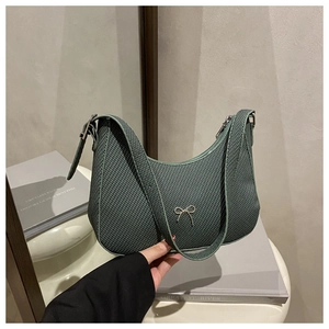Detail shot of green crescent moon bag with woven texture and metal bow decoration