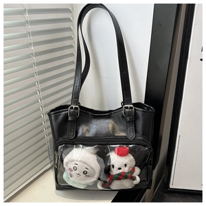 Detail of black PU leather tote bag featuring a transparent PVC pocket with plush dolls