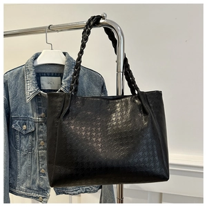 Détail du sac cabas en cuir noir avec gaufrage pied-de-poule et poignée tissée sur cintre