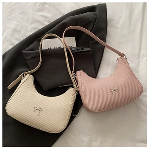 Detail showing woven texture and silver bow on cream and pink half-moon shoulder bags