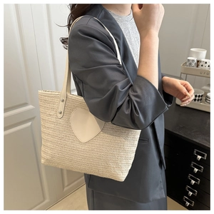 Détail du sac seau tissé crème avec patch cœur en cuir blanc et rivets argentés