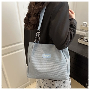 Détail du sac cabas tissé bleu clair avec bandoulière chaîne et étiquette de mode