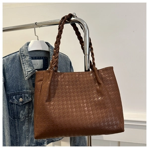 Détail d'un sac cabas marron avec textures d'étoiles et poignée tressée épaisse