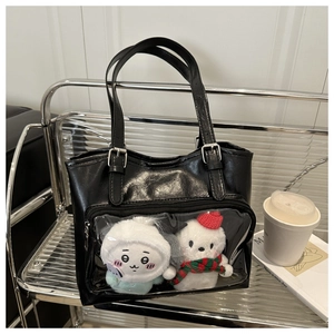Detail of black ita bag with transparent front pocket showing cute plush characters