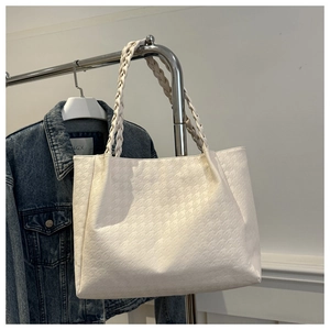 Détail de la poignée tressée et texture pied-de-poule sur grand sac fourre-tout blanc crème