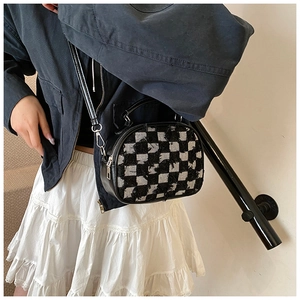 Detail of checkered tweed crossbody bag featuring fringe edges and silver hardware