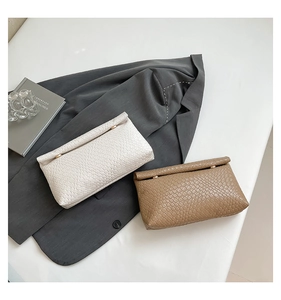 Detail of woven faux leather envelope clutch with metallic ring and chic textures
