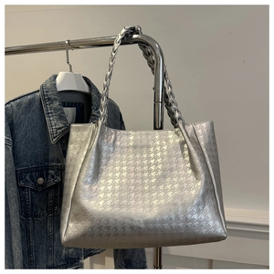 Détail d'un sac cabas argenté avec motif pied-de-poule et bandoulière tressée