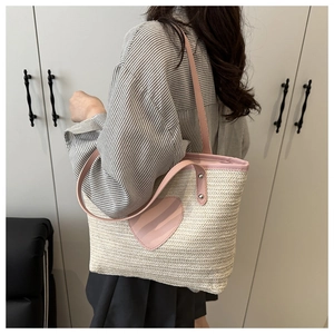 Détail du sac cabas en paille tressée avec patch cœur rose et bandoulières en cuir assorties