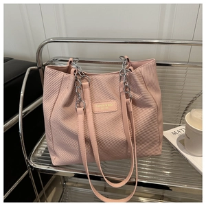 Detailed view of pink textured tote bag featuring a leather logo tag and chain strap