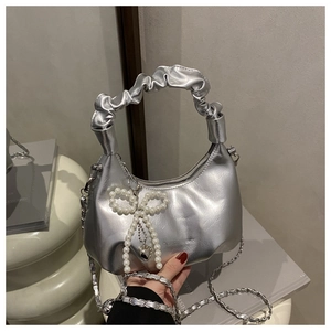 Detail of silver pleated handbag with beaded bow charm and chain strap texture