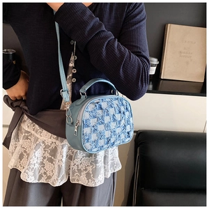 Detail of light blue checkered denim patchwork crossbody bag with fraying edges