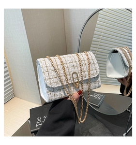 Detail of white tweed texture with gold sequins and metallic clasp on crossbody bag
