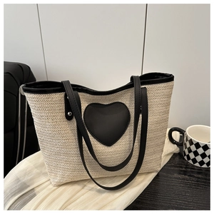 Détail de la texture en paille et du patch cœur en similicuir noir d'un sac d'été