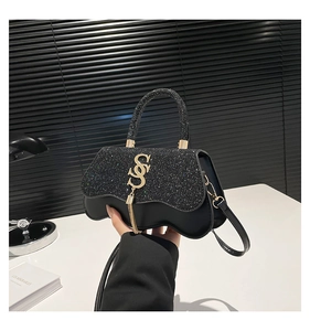 Detailed close-up of a black sequin crossbody bag featuring a gold S-shaped metal clasp