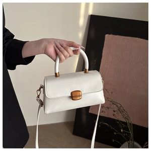 Close-up of a white leather handbag with a vintage gold lock and rectangular flap design