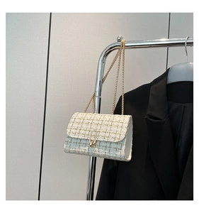 Detailed view of the plaid tweed fabric texture and gold metal clasp on a chain bag