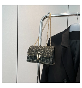 Detail of black tweed shoulder bag with gold chain strap and elegant metallic oval lock