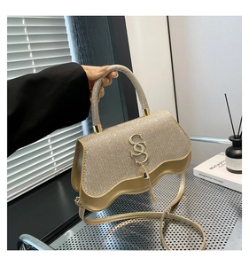 Close-up of champagne rhinestone handbag with crystal tassels and wave bottom design